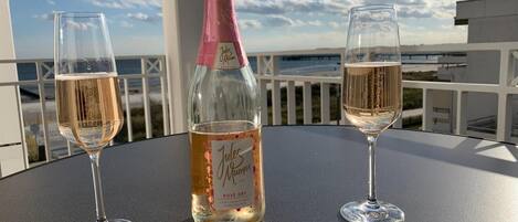 En flaske Jules Mumm Rose Dry champagne og to glas på et bord med havudsigt.