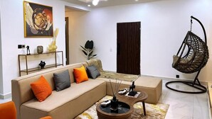 Ein modernes Wohnzimmer mit einem beigefarbenen Ecksofa, einem Hängesessel und einem einzigartigen Couchtisch.