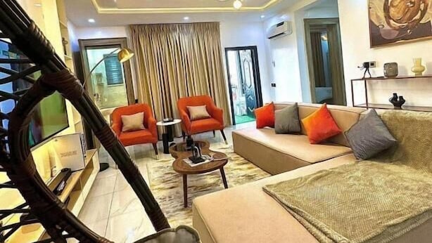 Ein modernes Wohnzimmer mit einer Couch, zwei Sesseln, einem Couchtisch und einem Deckenventilator.