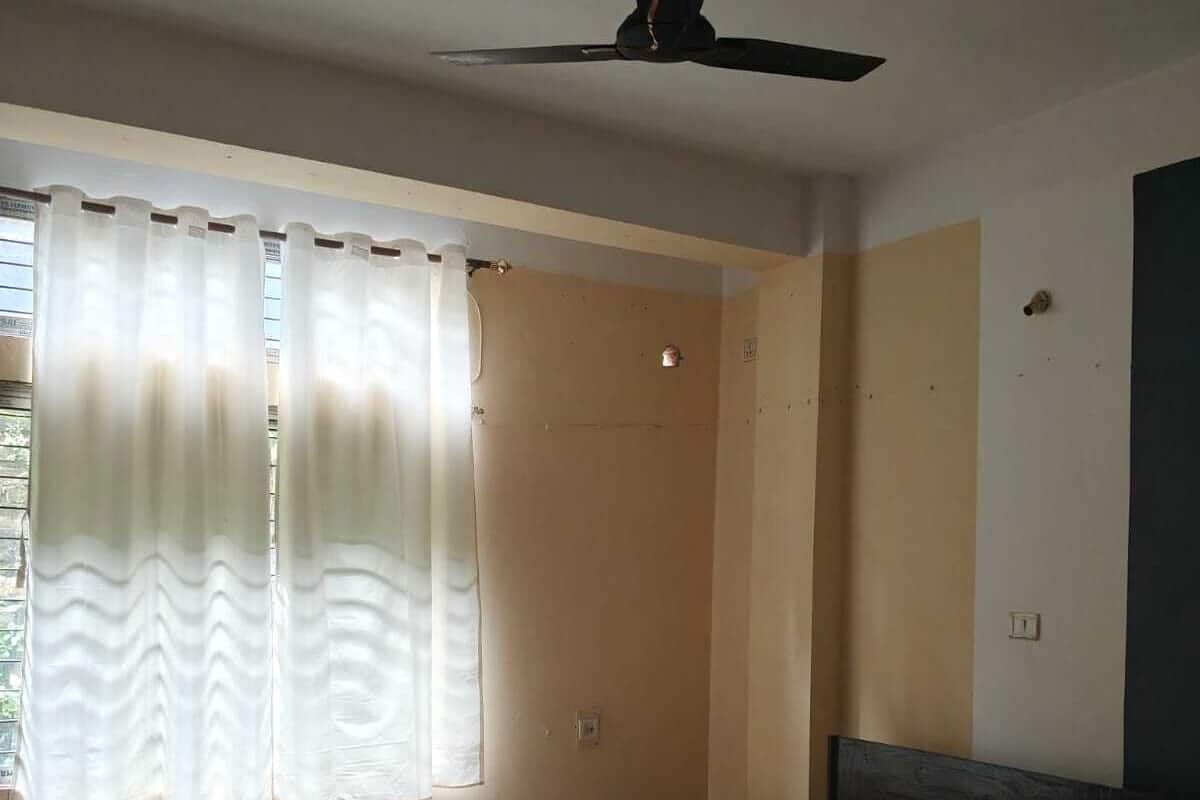 A bedroom with a bed, a ceiling fan, a window with curtains, and a door.