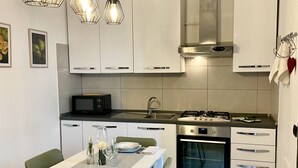 A modern kitchen with white cabinets, stainless steel appliances, and a dining area with a table set for two.