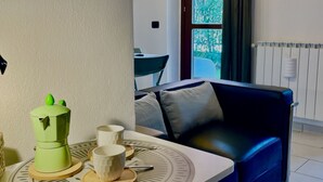 A modern living room with a blue sofa, a coffee maker, and two white cups on a round table.