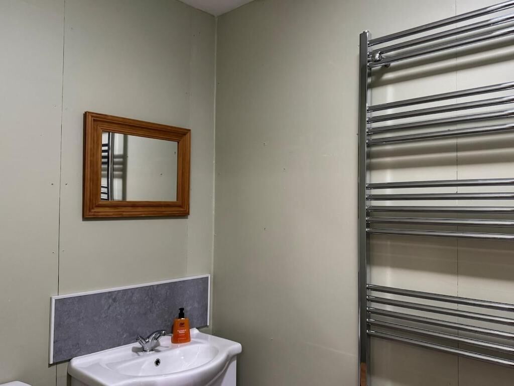 Een badkamer met een witte wastafel, een spiegel en een handdoekhouder.
