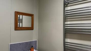 Een badkamer met een witte wastafel, een spiegel en een handdoekhouder.
