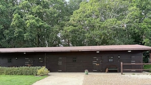 A long, single-story building with a gravel driveway and a green lawn. - The Riley Stable- Cozy Getaway (Waterlooville)