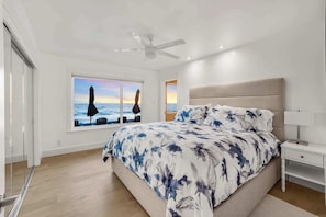 A bedroom with a bed, a nightstand, a ceiling fan, and a window with a view of the sea. - @marbella Lane-oceanfront Retreat w/ Stunning View (Pacifica)