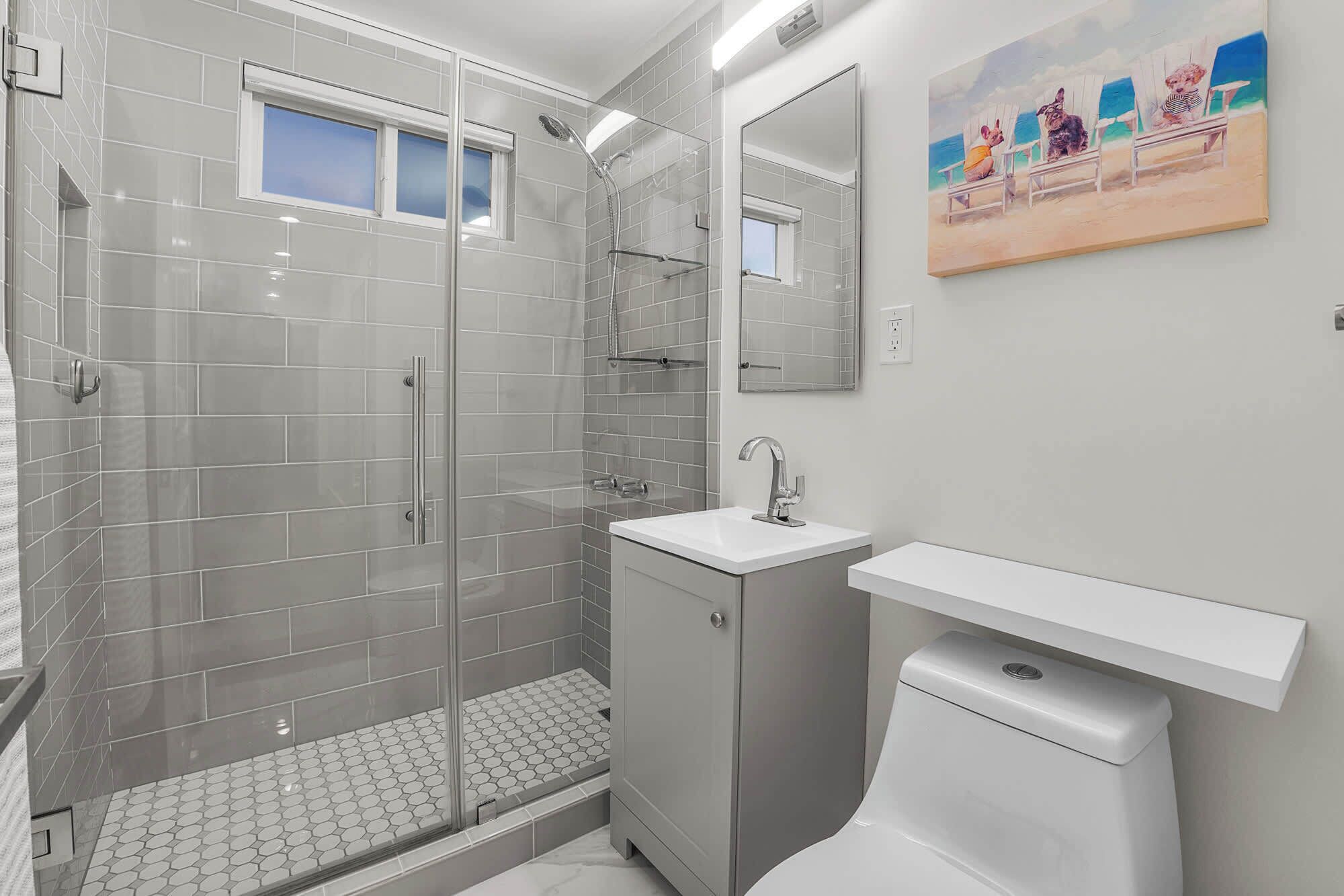 A modern bathroom with a glass-enclosed shower, a white sink, and a toilet.