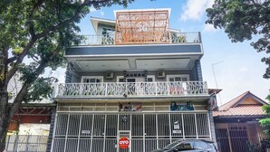 Un edificio de varios pisos con una entrada protegida por una reja, un balcón con barandilla y un letrero que indica una red 3G.