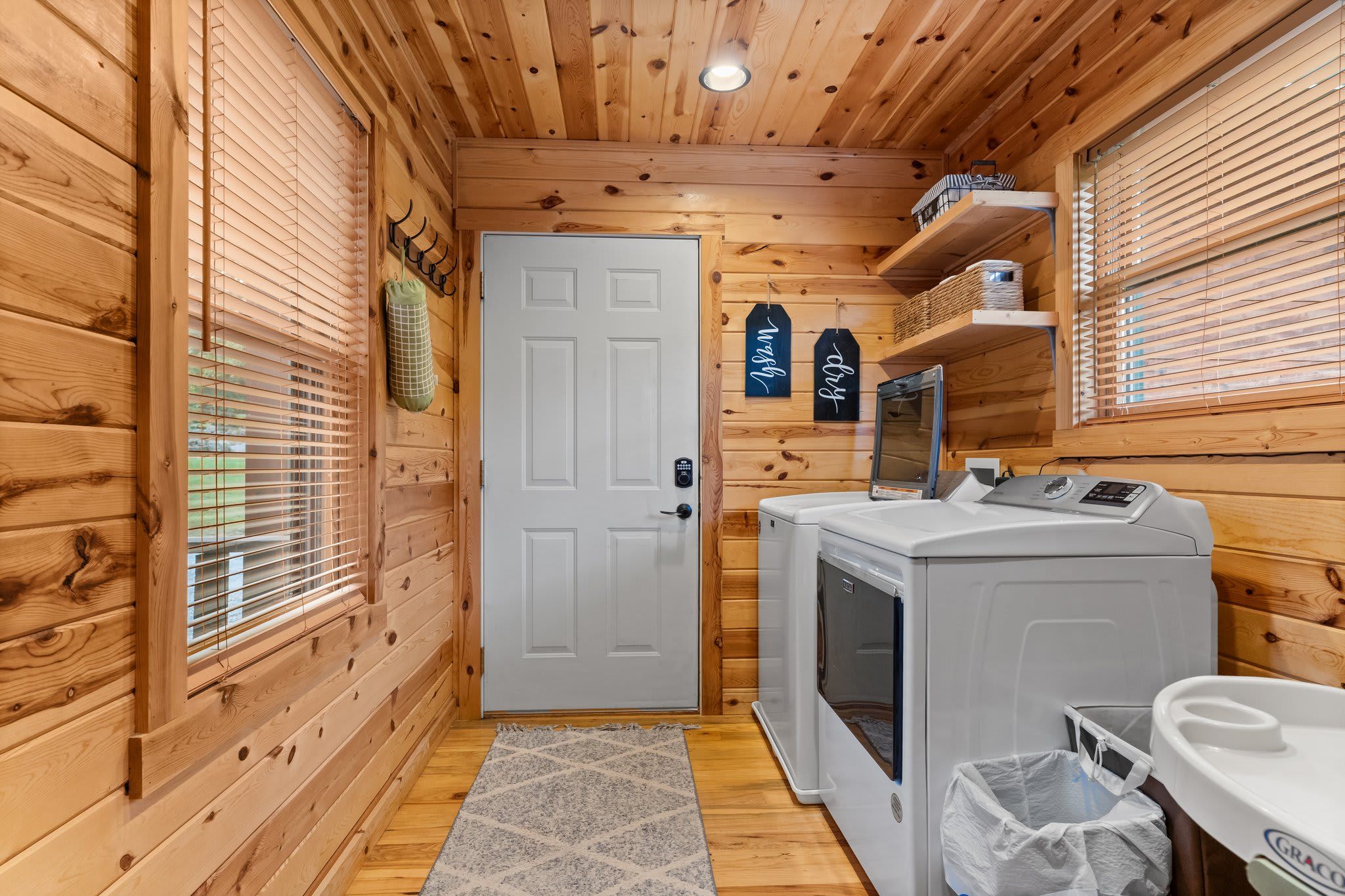 A compact laundry room with wooden walls, a white door, and a washing machine.