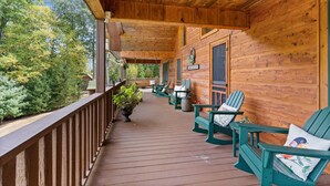 Une terrasse en bois avec des fauteuils Adirondack verts et une plante en pot.