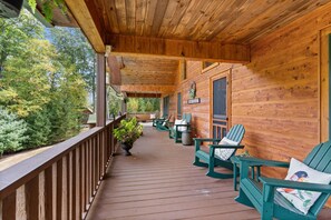 Une terrasse en bois avec des fauteuils Adirondack verts et une plante en pot.