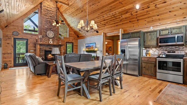 L’intérieur d’un chalet rustique comprenant un coin repas, une cuisine et une cheminée.