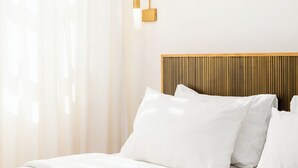 A neatly made bed with white linens, a wooden headboard, and a wall-mounted light fixture. - Zoe by halu (Thessaloniki)
