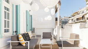 A rooftop terrace with outdoor seating, including a sofa and chairs, a small table, and hanging paper lanterns. - Zoe by halu (Thessaloniki)