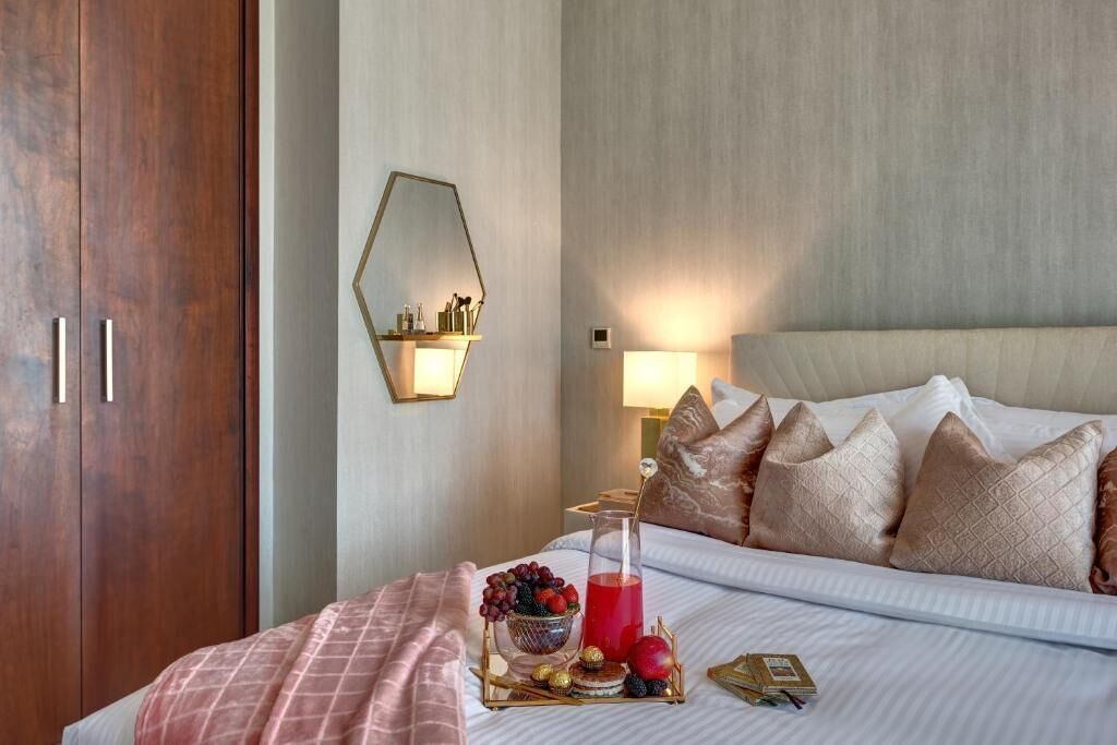 Ein Hotelzimmer mit Bett, Nachttisch mit Lampe, Spiegel und einem Holzschrank.