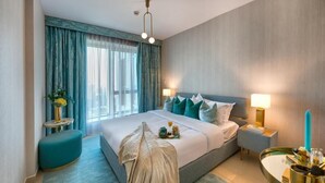 A modern hotel room with a large bed, two bedside lamps, a nightstand, a round mirror, and a view of the outdoors through the window. - Durrani Homes - Designer 2BR Apt with stunning Burj Khalifa and Fountain View (Dubai)