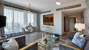 A modern hotel room with a living area, dining space, and a view of the city. - Durrani Homes - Designer 2BR Apt with stunning Burj Khalifa and Fountain View (Dubai)