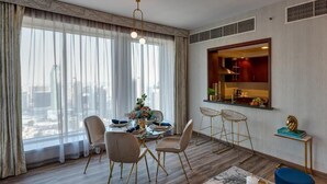 A modern living room with a dining area, large windows, and a view of the city. - Durrani Homes - Designer 2BR Apt with stunning Burj Khalifa and Fountain View (Dubai)