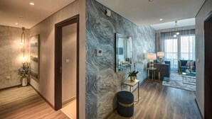 A modern living room with a marble wall, a large mirror, and a seating area with a sofa and a coffee table. - Durrani Homes - Designer 2BR Apt with stunning Burj Khalifa and Fountain View (Dubai)