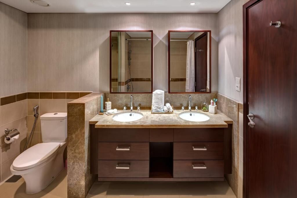 Une salle de bain avec deux lavabos, des toilettes et une douche.
