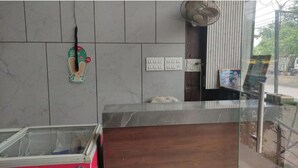 Ένας χώρος υποδοχής με μαρμάρινο τοίχο, έναν γυάλινο πάγκο, έναν ανεμιστήρα και μια φωτογραφία σε κορνίζα στον τοίχο.