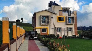 A modern two-story house with a paved driveway leading to the entrance. - Rose garden enclave for families  (Ooty)