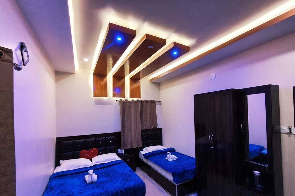 A hotel room with two beds, a wardrobe, and a mirror.