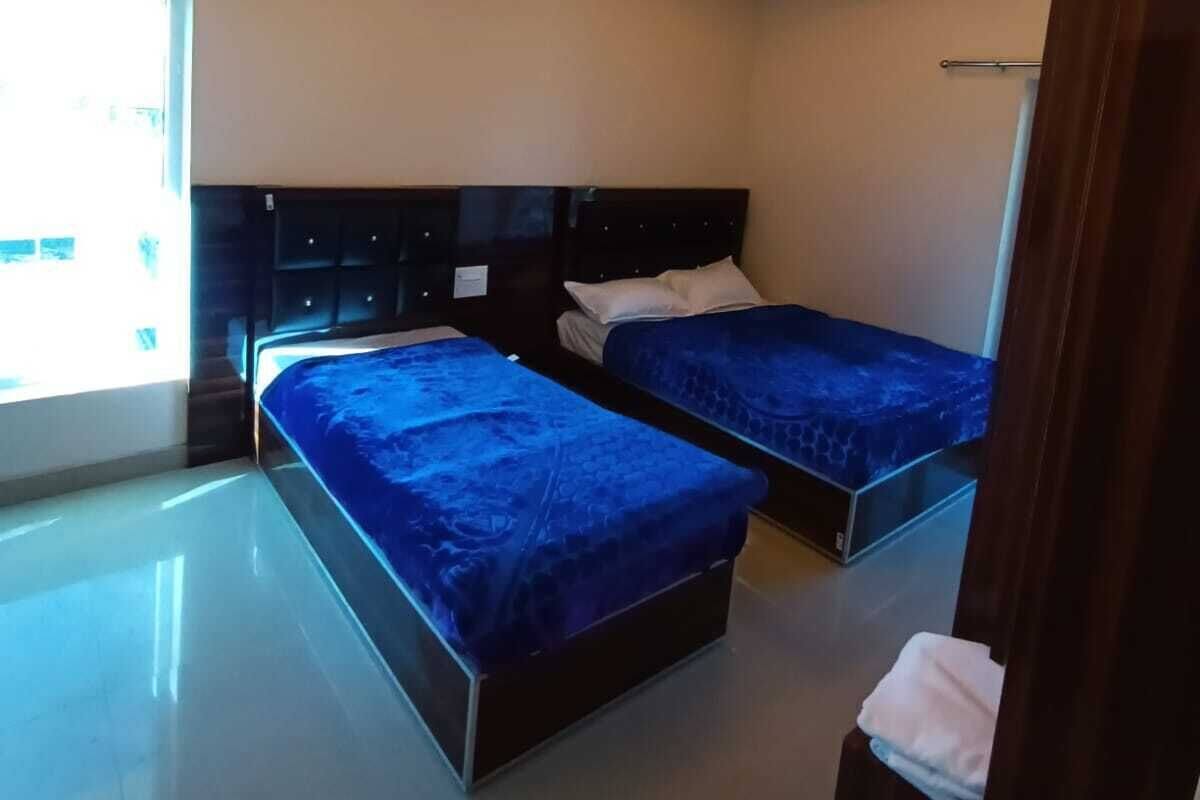 A modern hotel room with two beds, a large window, and a curved ceiling light fixture.