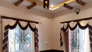 A room with a marble floor, built-in seating, a ceiling with wooden beams, and a large window with curtains. - Rose garden enclave for families  (Ooty)