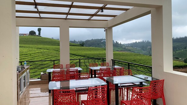 A terrace with tables and chairs, offering a view of terraced fields. - Rose garden enclave for families  (Ooty)