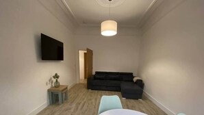 Ein modernes Wohnzimmer mit einer Couch, einem kleinen Tisch mit einer Vase und einem runden Tisch mit Stühlen.