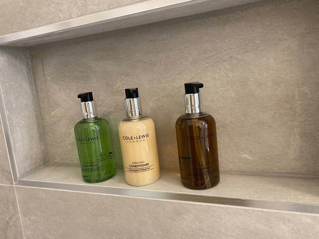 Three bottles of body wash and conditioner on a shelf.