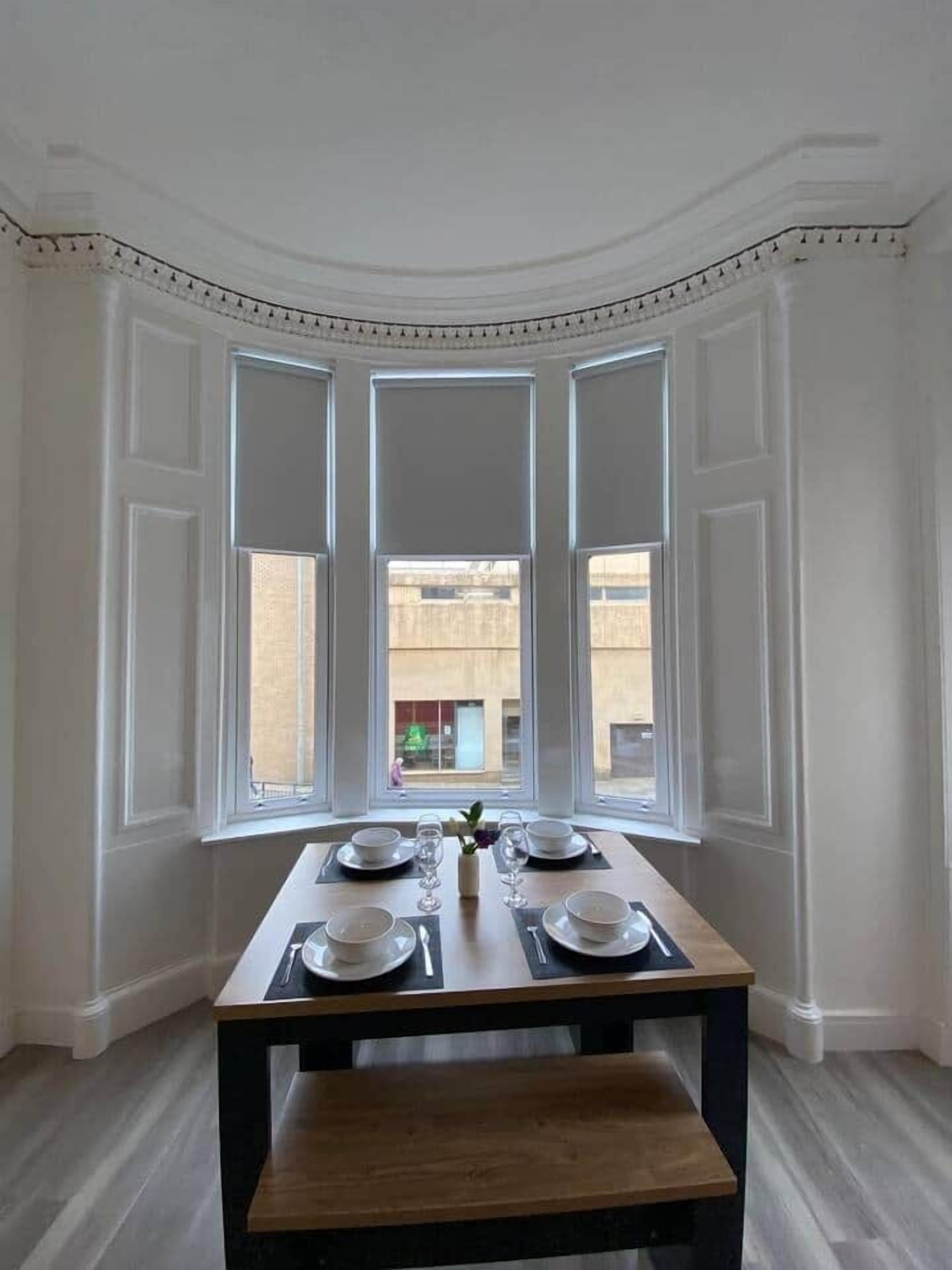 A dining area with a table set for four, large windows, and a view of the outside.