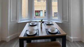Een eetgedeelte met een tafel voor vier personen, grote ramen en uitzicht op het buitenlands gebied.