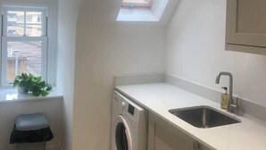 A compact kitchen with a built-in washing machine, a sink, and a skylight.