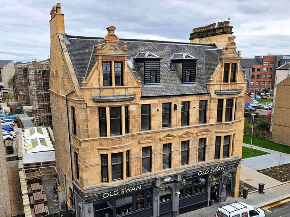 A historic building with a corner entrance, a shop on the ground floor, and a staircase leading to the upper floors.