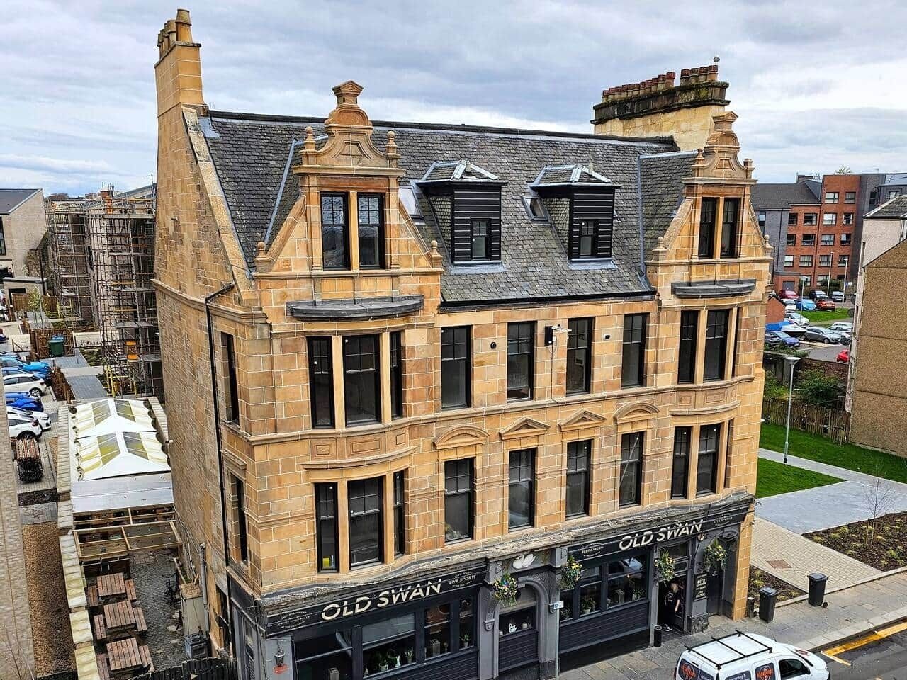 A historic building with a corner entrance, a shop on the ground floor, and a staircase leading to the upper floors.