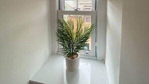 Une fenêtre d’angle avec un pot de fleurs.