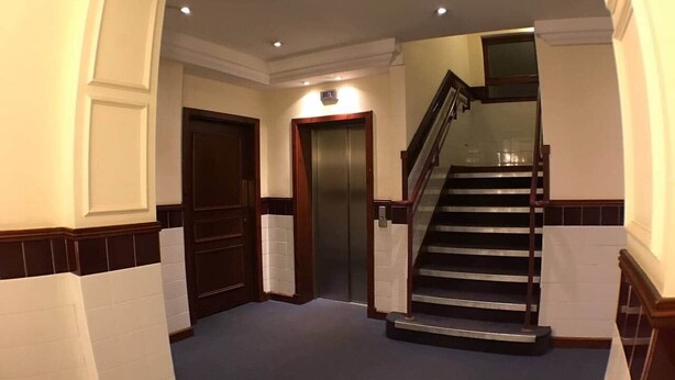 Un pasillo con una escalera, un ascensor y una puerta.