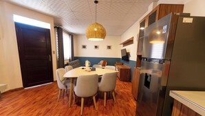 Una cuina moderna amb nevera d'acer inoxidable, armaris de fusta i taula de dinar amb caires.