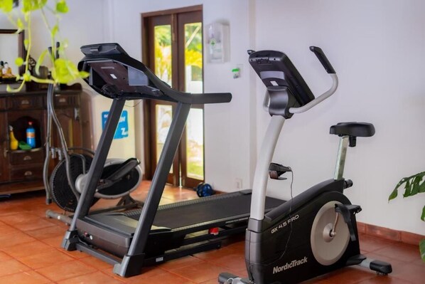 A home gym with a treadmill and an elliptical machine.