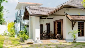 A two-story house with a tiled roof, a staircase, and a front porch with a dog statue. - Ashlar Villa (Galle)