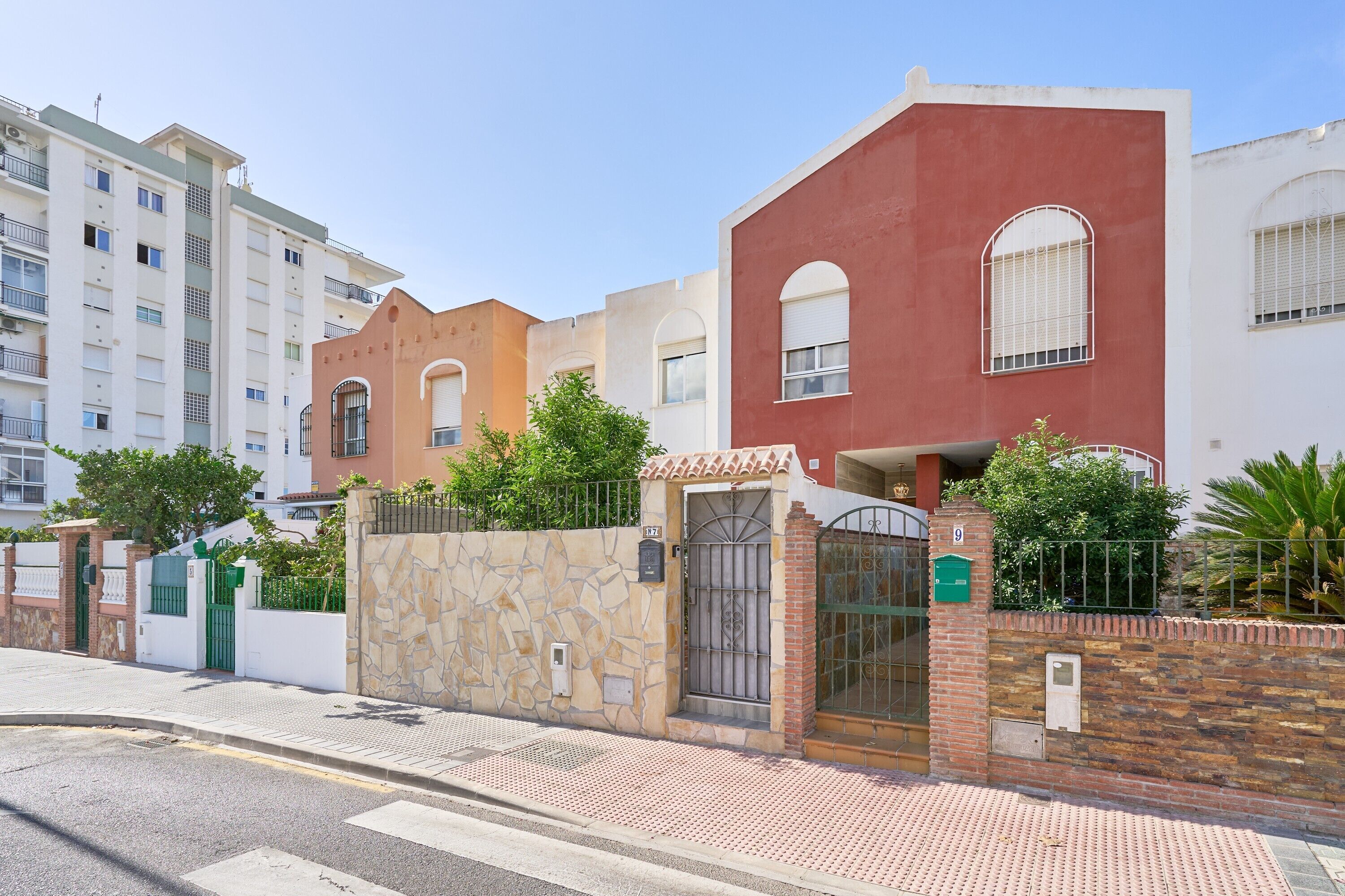 Un immeuble résidentiel doté d’une entrée sécurisée par un portail, d’un mur en pierre et d’une terrasse carrelée.