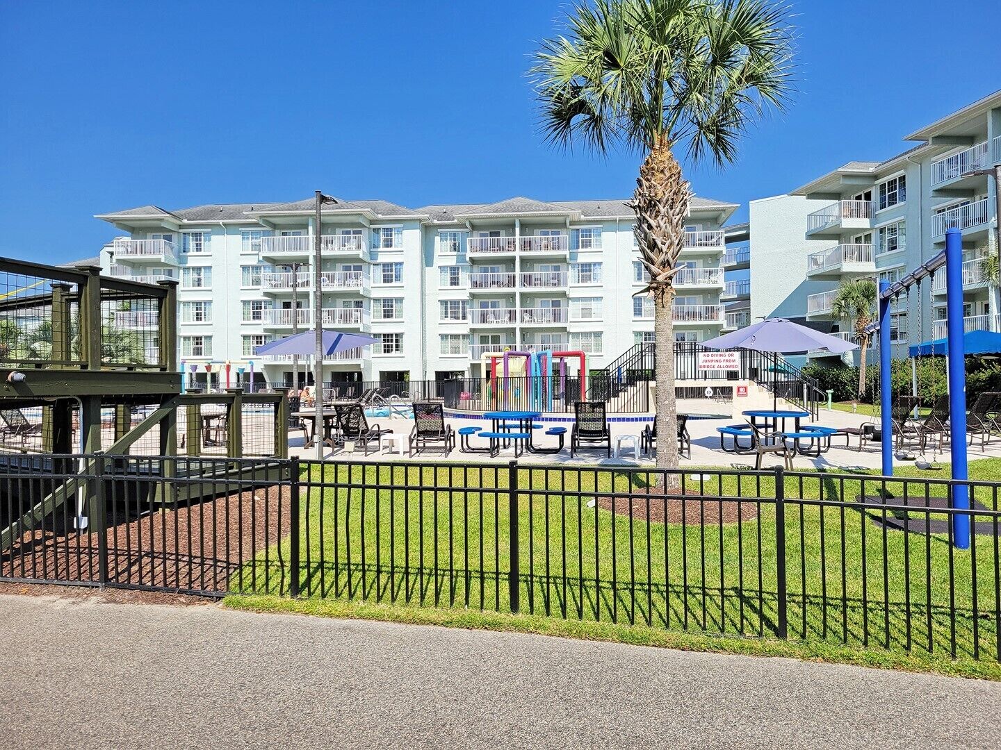 A resort with multiple-story buildings, outdoor pool, and exercise equipment.