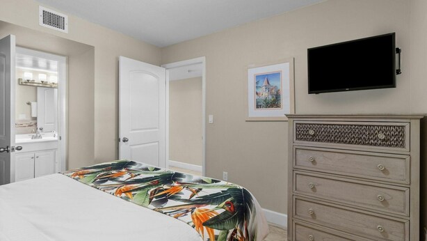 A bedroom with a bed, a dresser, a television, and a door.