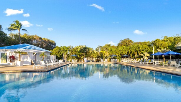 A clear swimming pool with lounge chairs and umbrellas, surrounded by trees and a gazebo. - Family-Friendly 1BR w/ Partial Ocean View & Pool (Tavernier)