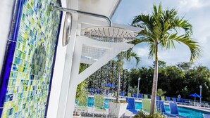 Zona de piscina con fuente, palmeras y sillas de descanso.