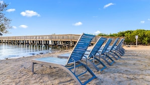A beach with blue lounge chairs and a wooden pier extending into the water. - Key Largo 1BR - Ocean View, Near Founders Park (Tavernier)