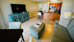 A living room with a TV, ottoman, and sofa, a kitchen with a microwave and stove, and a ceiling fan. - Key Largo 1BR - Ocean View, Near Founders Park (Tavernier)