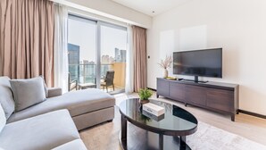A modern living room with a sofa, a glass coffee table, a TV, and a balcony with a city view.
